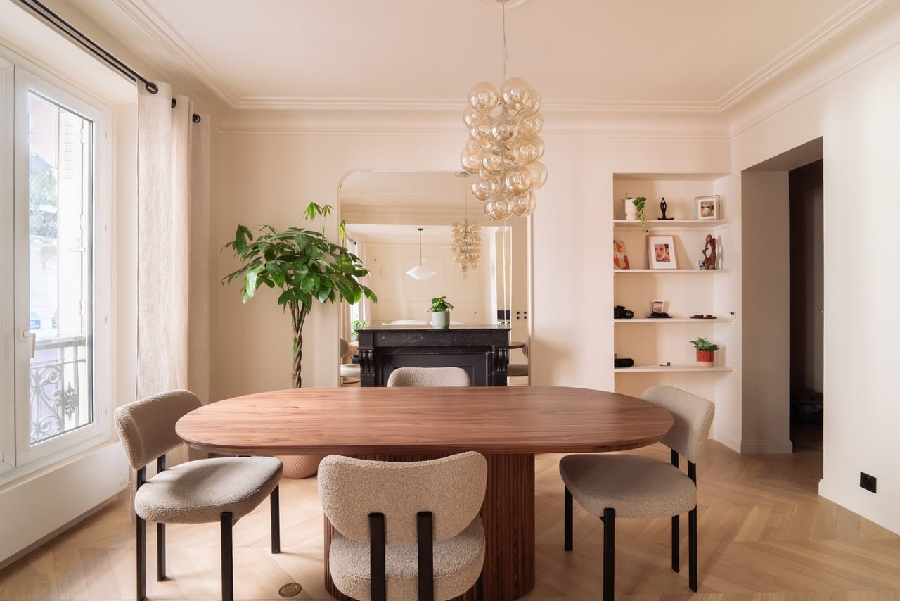 Séjour avec table ovale en noyer, lustre en verre et bibliothèque